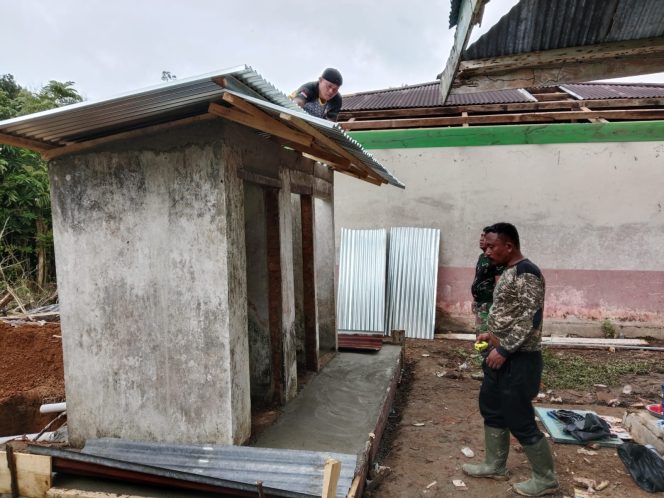 
 Anggota Satgas TMMD dan Warga Gotongroyong Memasangan Atap Seng